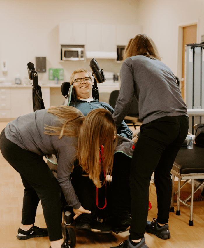 A physical therapist and a volunteer working together to help a client who is in a wheelchair