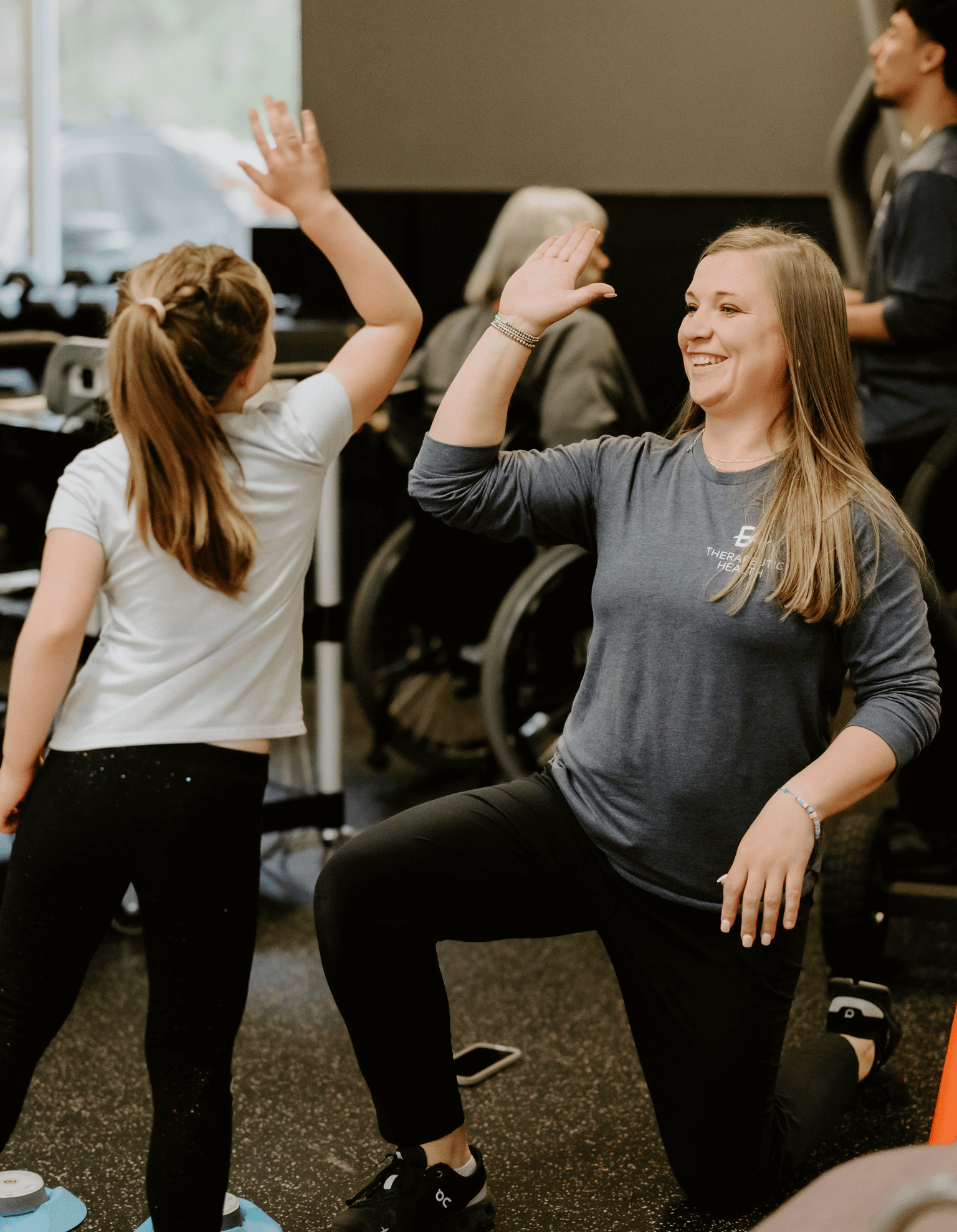 physical therapist giving young client a high five during physical therapy session